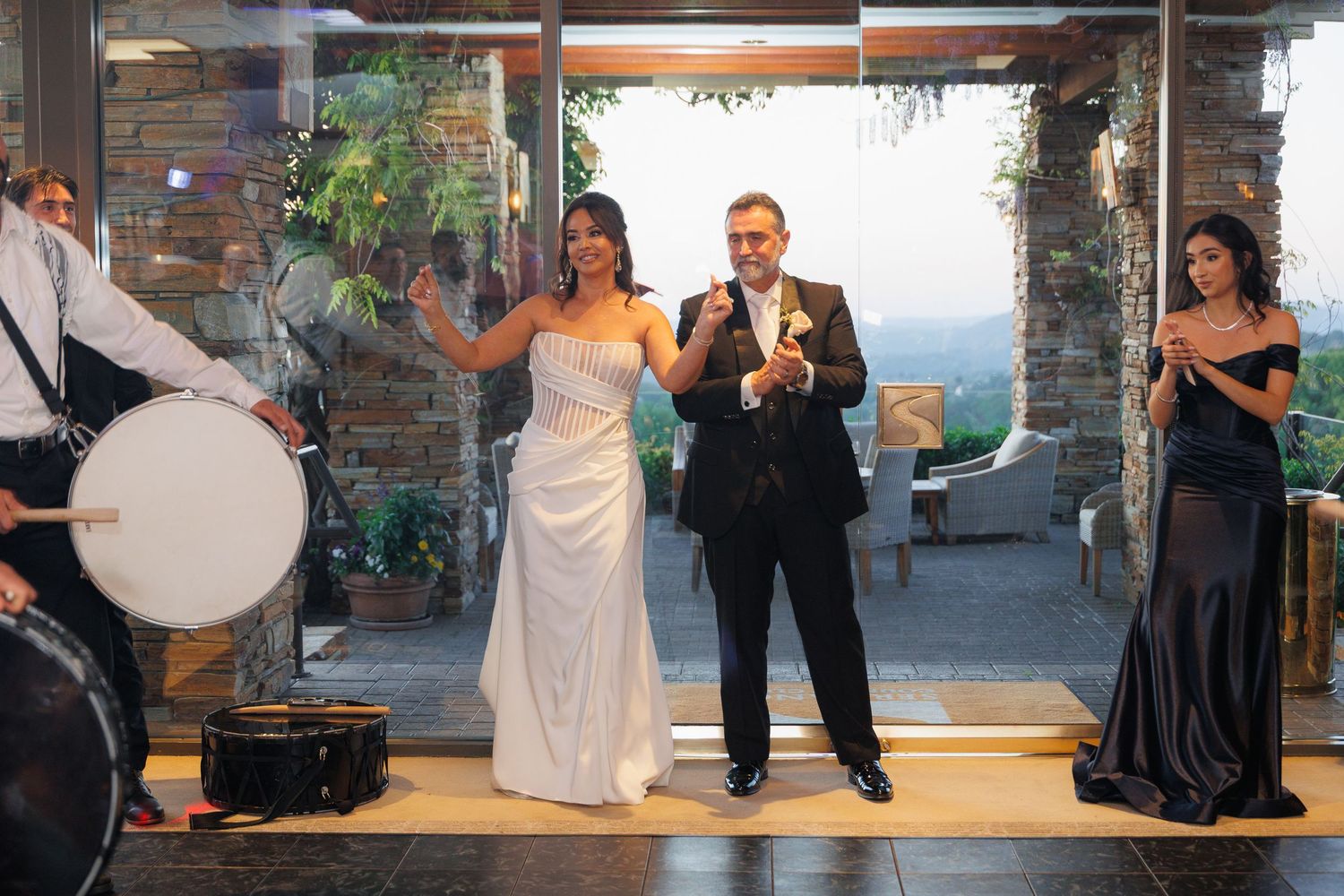 Wedding party members dance and celebrate on a wooden dance floor during an indoor reception.