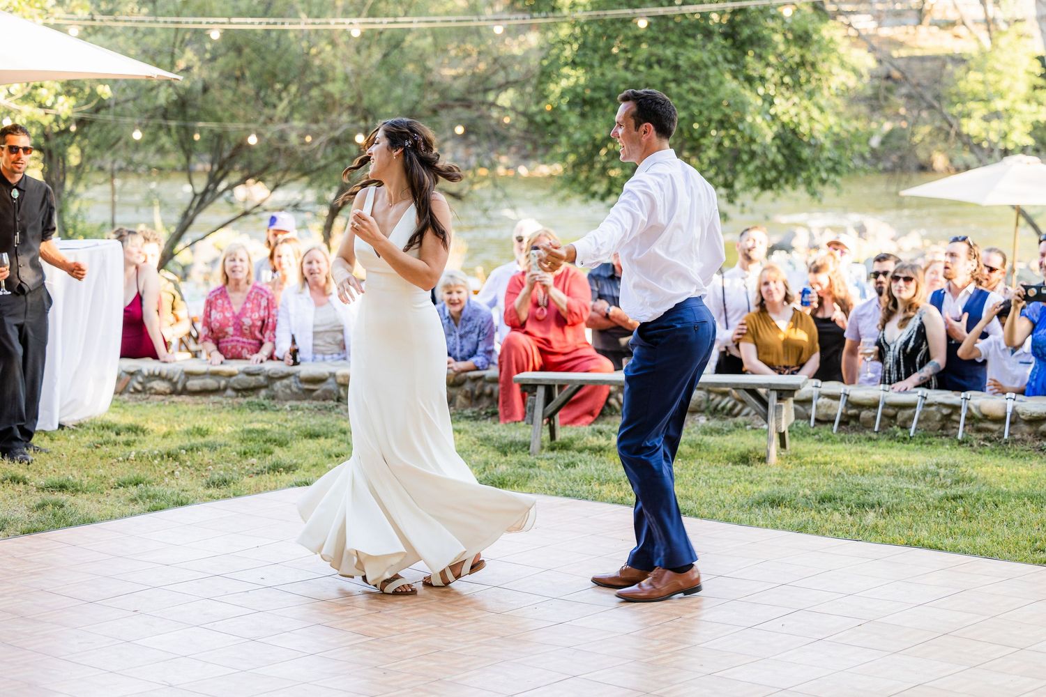 A couple shares a romantic dance moment on an outdoor stone patio during a wedding celebration.