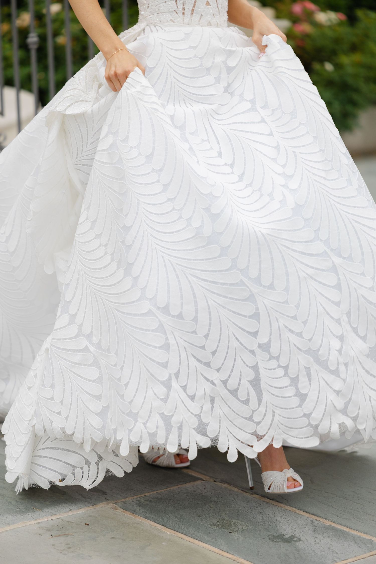 Close-up shots of a white wedding dress with delicate lace patterns as the wearer walks, showing intricate details and movement.