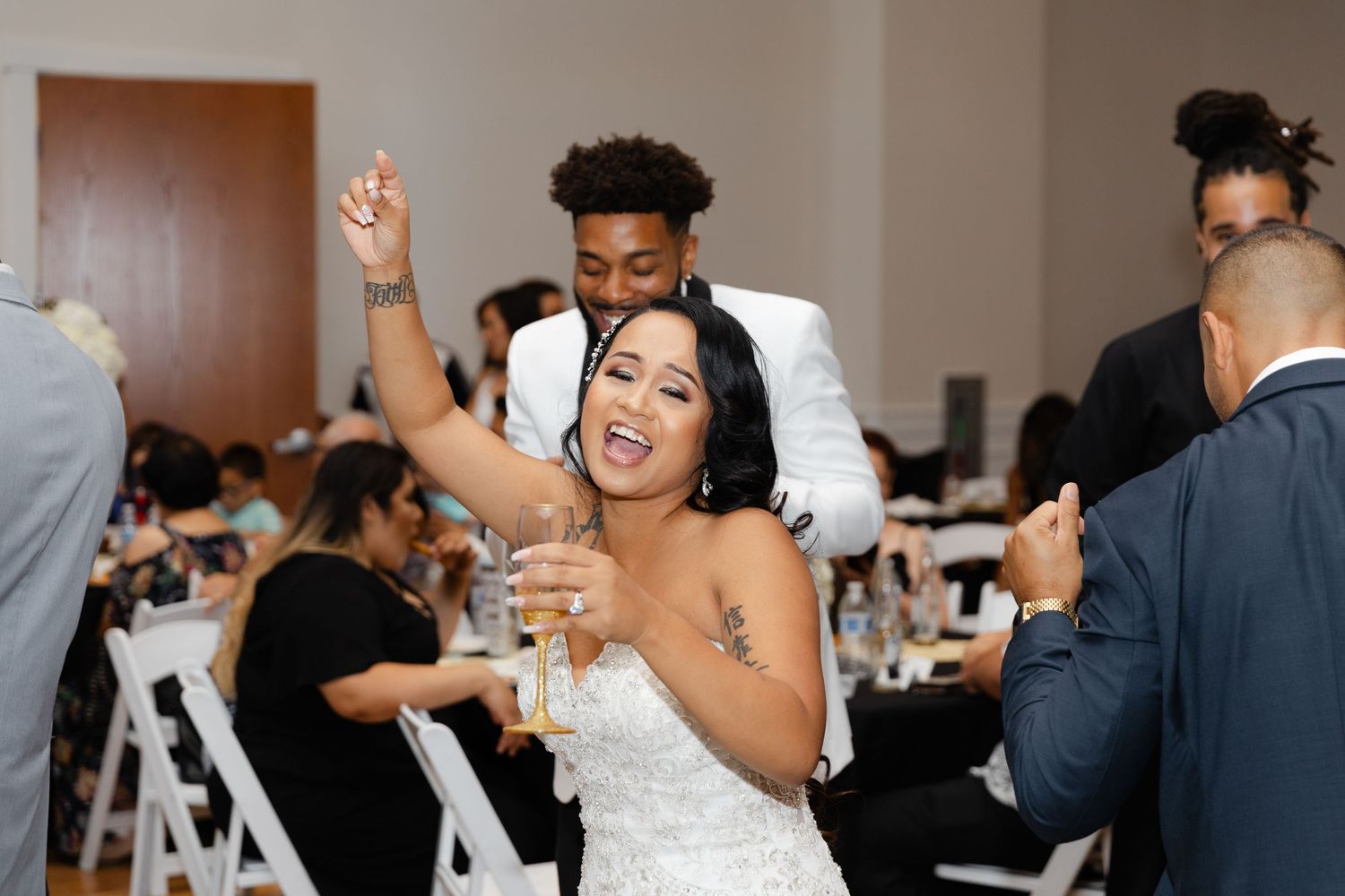 Wedding guests dance and celebrate energetically on a dance floor at a lively reception party.