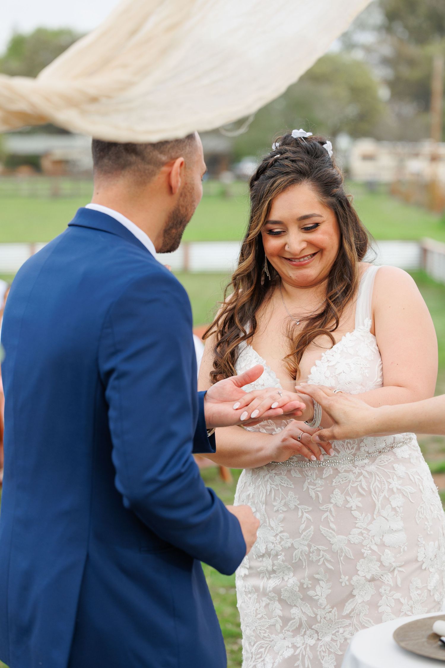 A couple shares an intimate moment during their wedding ring exchange ceremony outdoors.