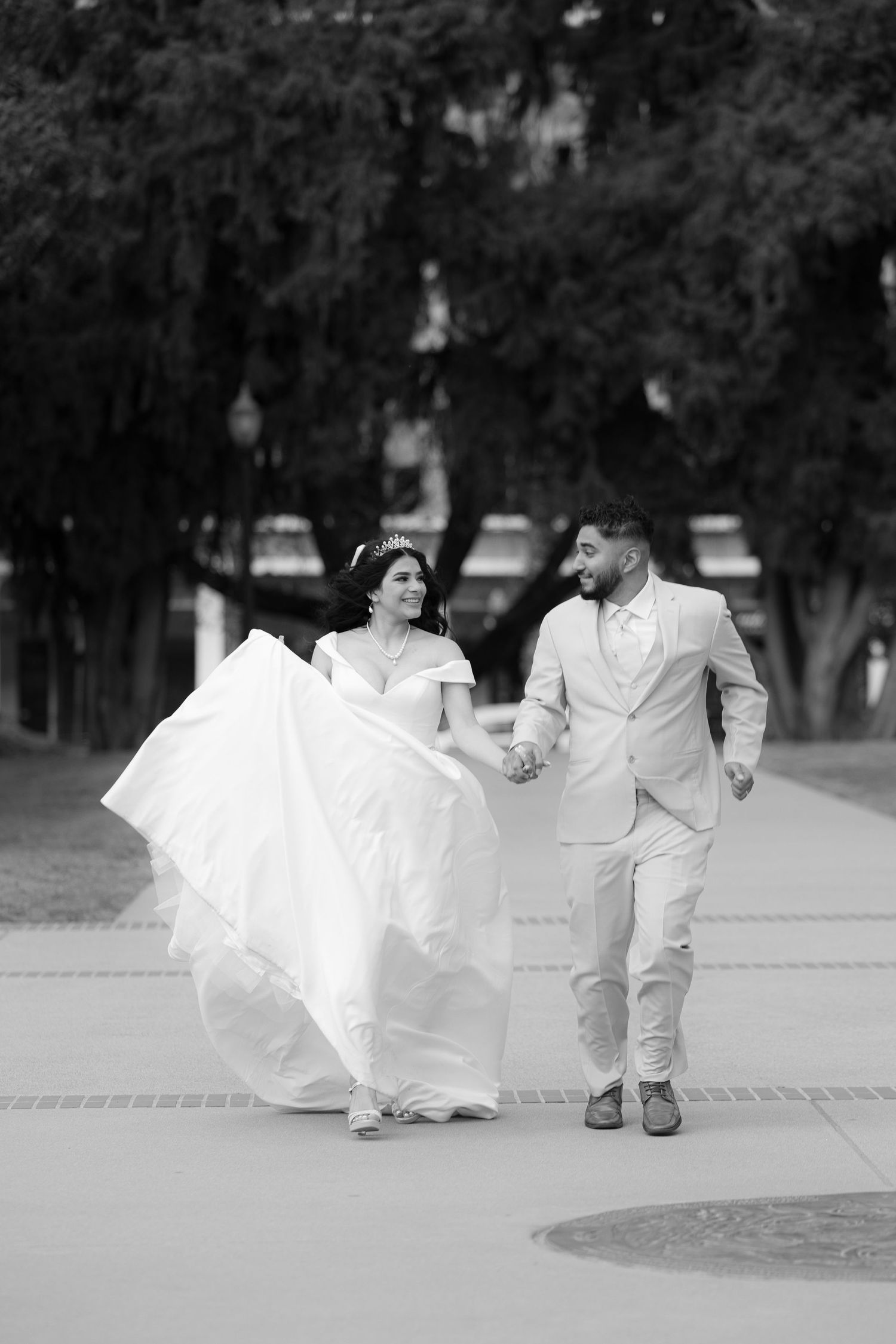 Black and white photo of couple running playfully together on paved walkway.