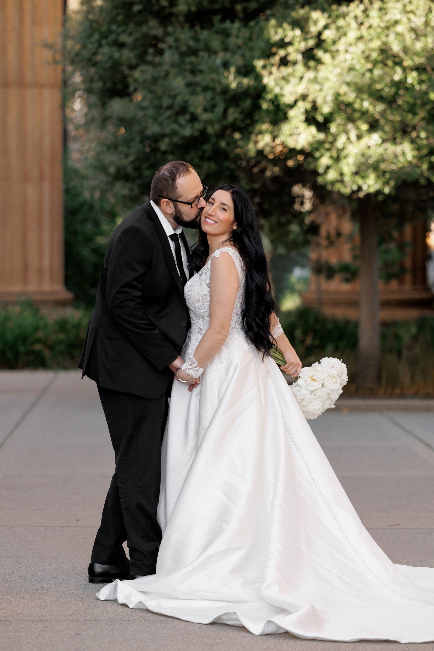 A romantic wedding couple in formal attire shares intimate moments during an outdoor photo session.