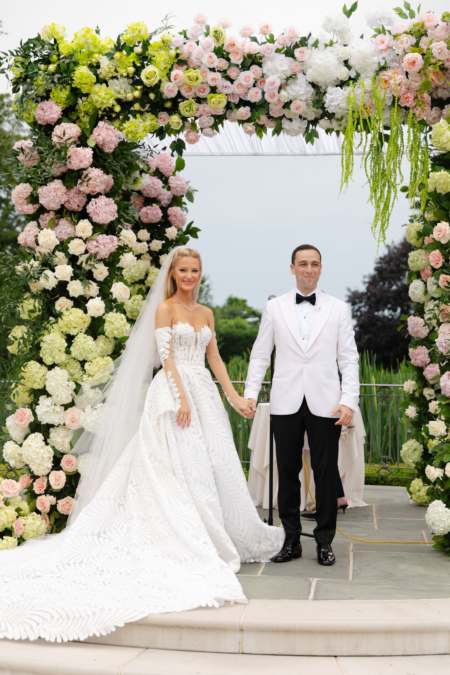 Elegant outdoor wedding ceremony setup with floral arches and decor in shades of pink and white roses.
