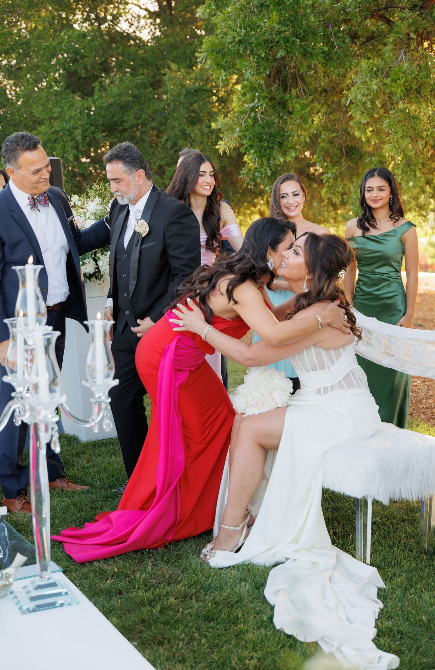 Wedding party enjoys candid moments on the lawn with decorative white lanterns during outdoor celebration.