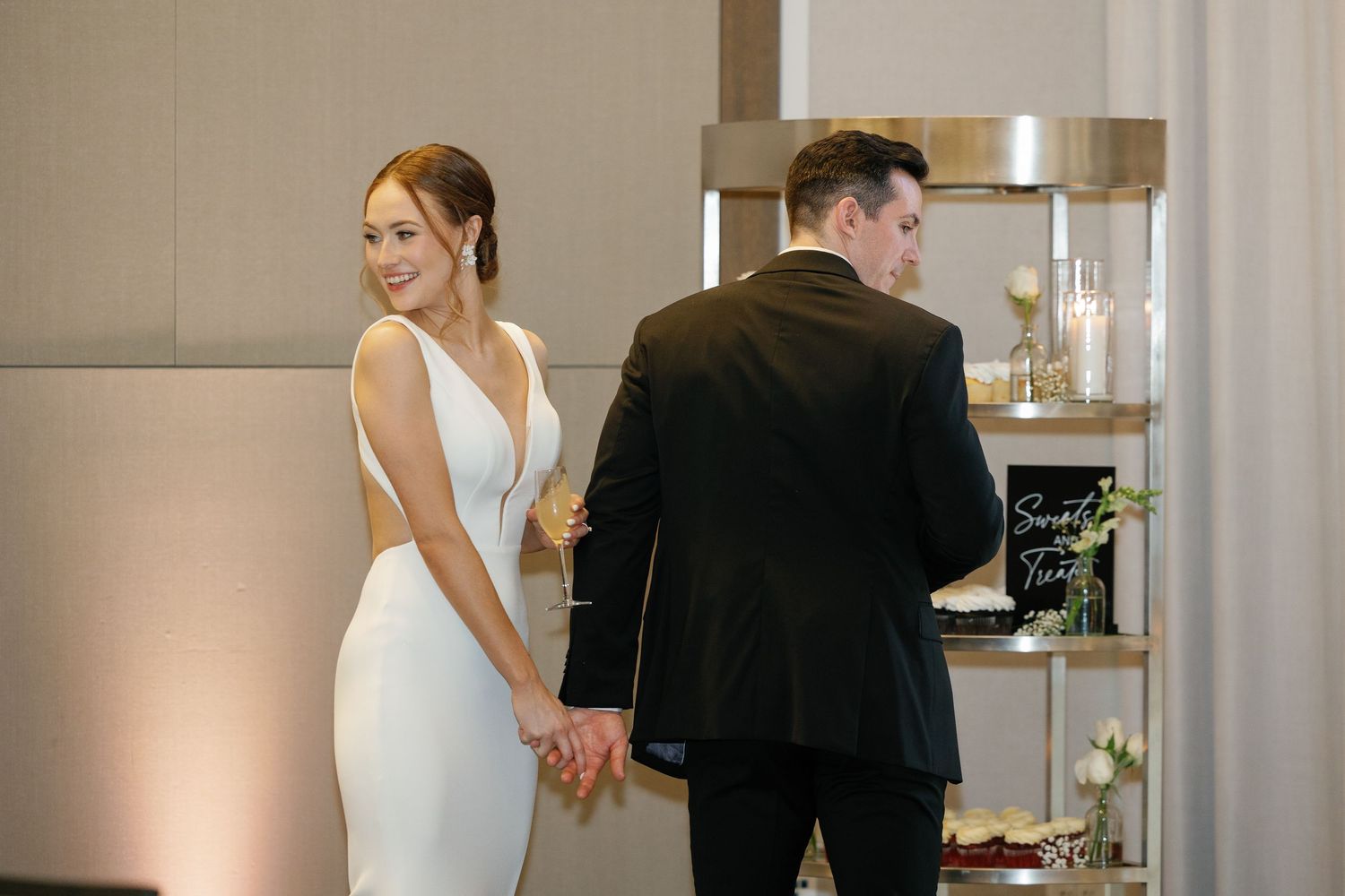 A bride and groom cut their elegant white wedding cake together at their reception celebration.