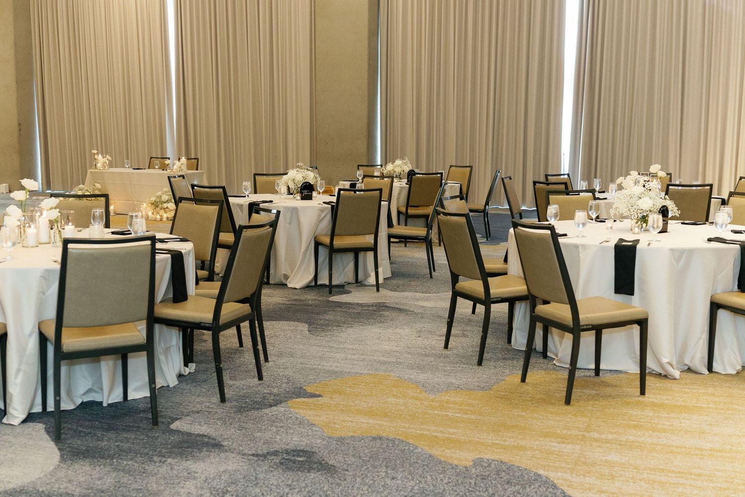 Modern banquet hall with elegant table settings and chairs arranged in rows for a formal event.