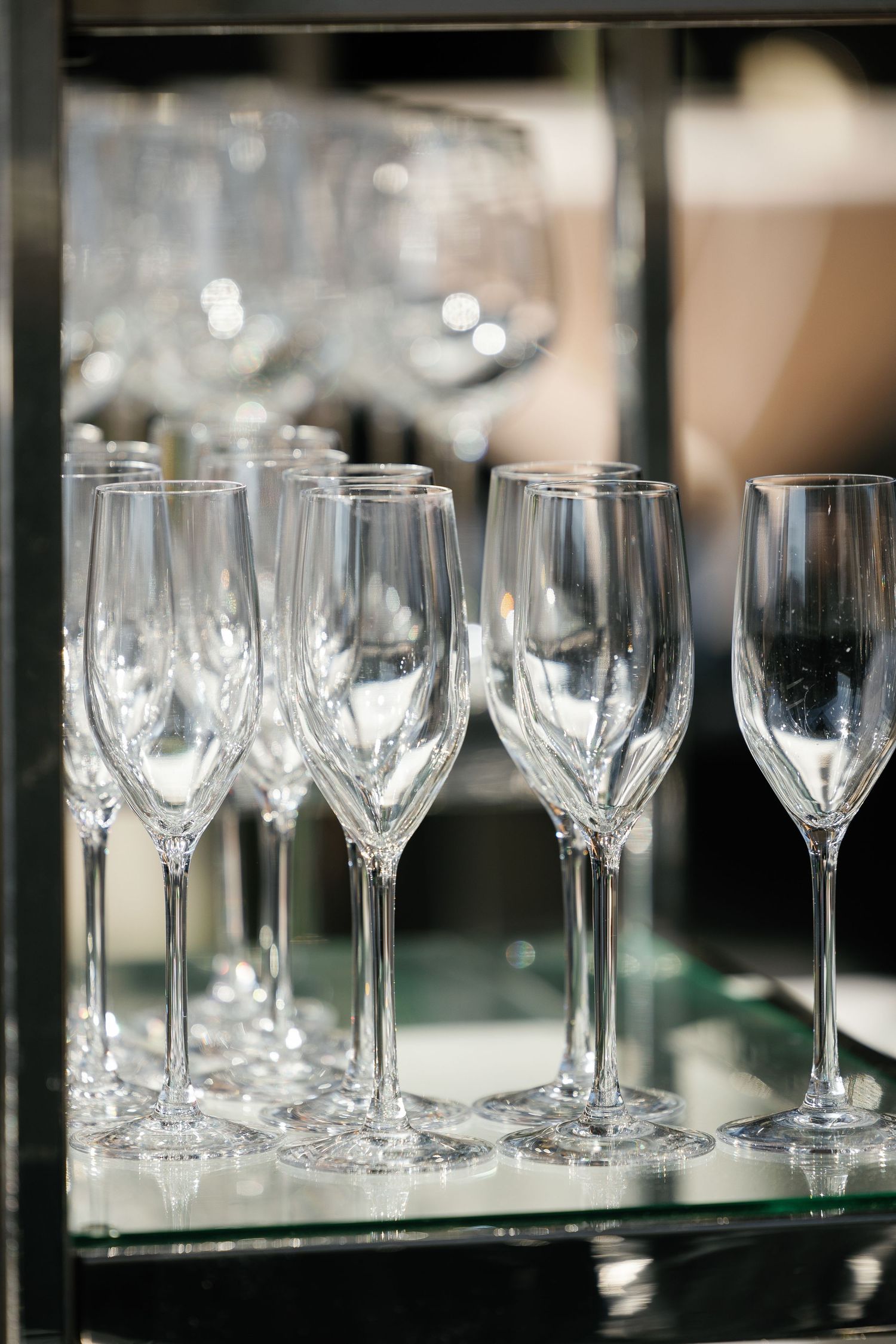 Empty crystal champagne flutes arranged on a reflective surface with soft bokeh lighting in the background.