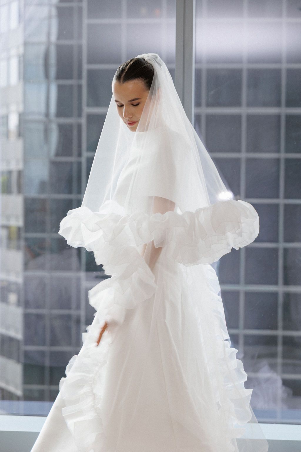 Ethereal bridal portraits featuring a white wedding gown with ruffled details and flowing veil in natural light.