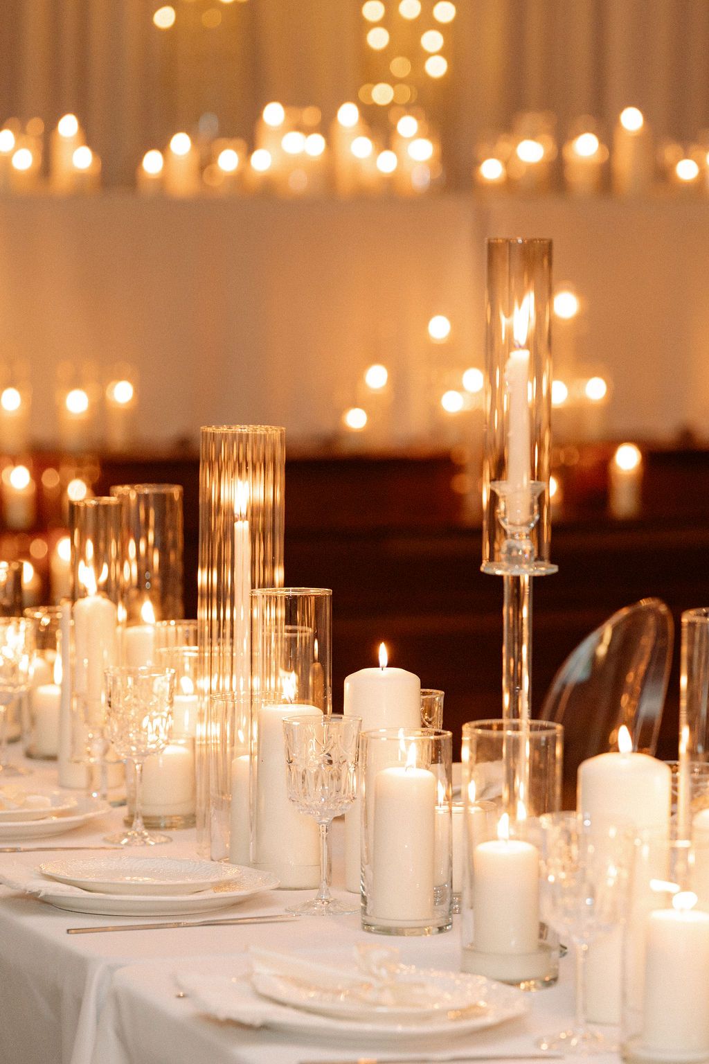 Elegant wedding table setting with glowing white candles and crystal holders creating romantic ambient lighting.