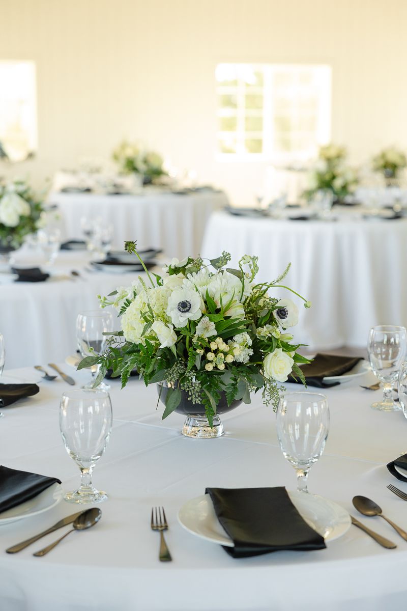 Modern wedding table settings with crisp white linens, black napkins, and fresh white floral centerpieces.