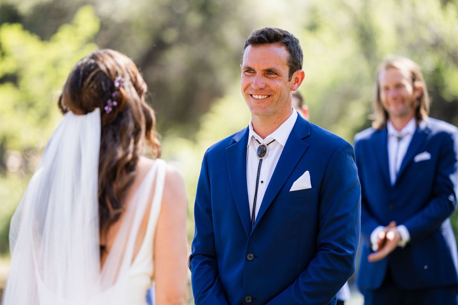 A couple shares a joyful moment during their outdoor wedding ceremony with an officiant in the background.