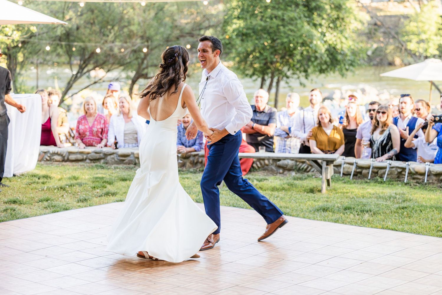 Wedding guests dance and celebrate on an outdoor patio during a summer reception.