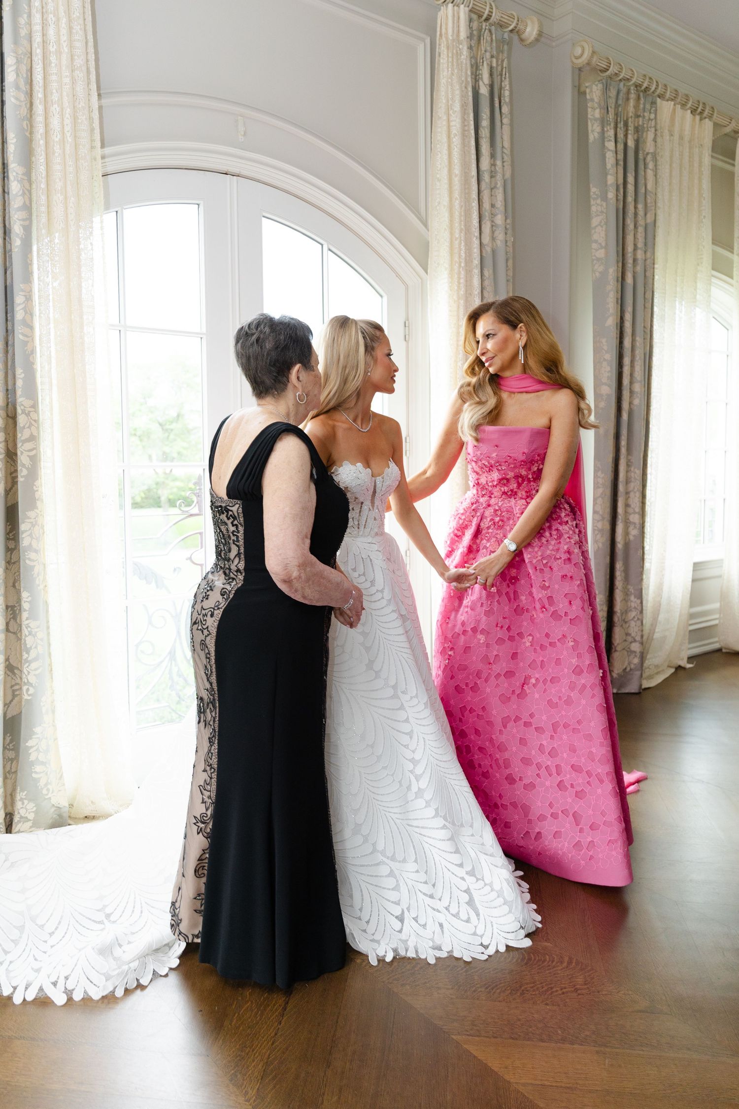 A sequence of photos showing two people in black and pink dresses dancing and twirling in an elegant white room.