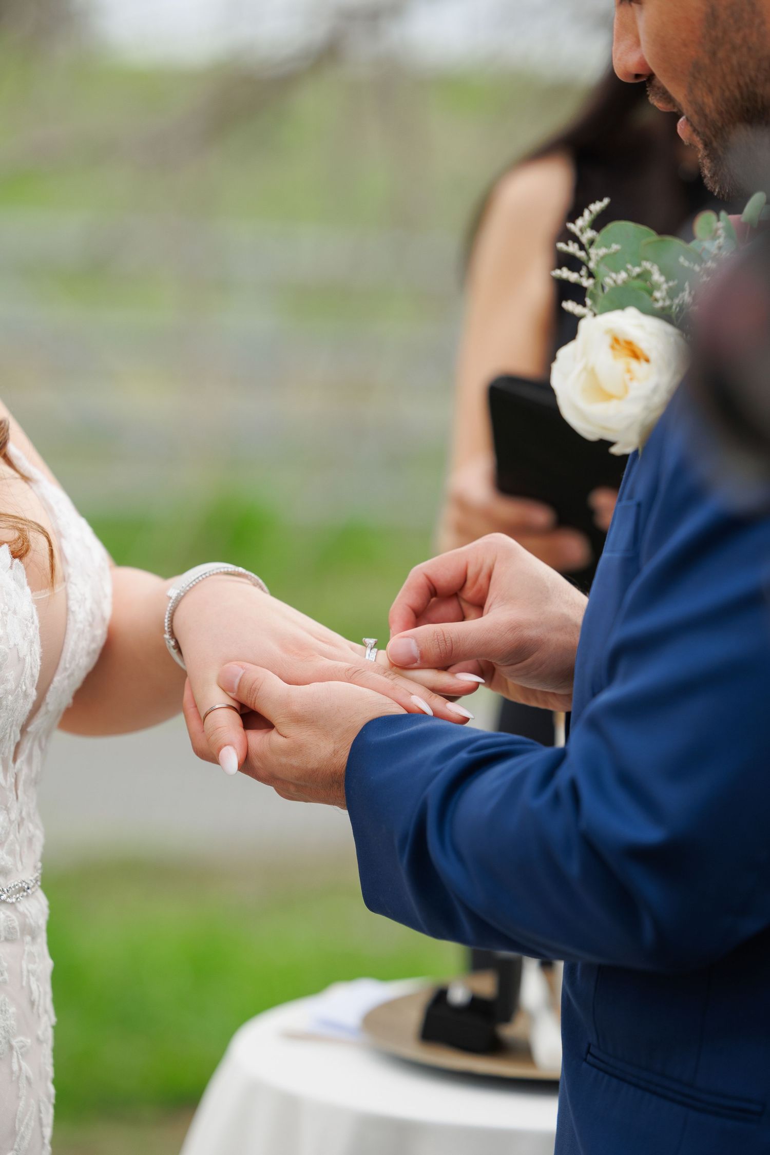 Close-up shot of hands exchanging wedding rings during an outdoor ceremony.