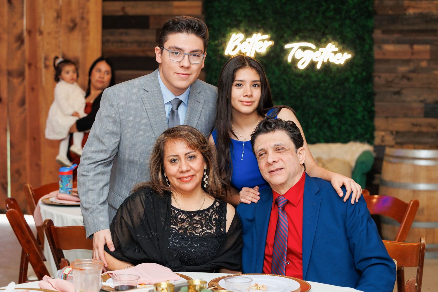 Wedding guests smile and celebrate at a rustic venue with wooden walls and warm lighting.