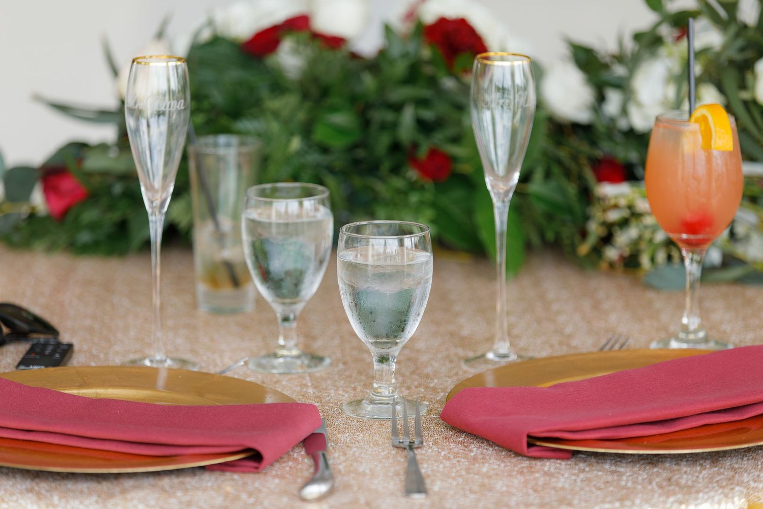 Elegant table settings with champagne flutes and coral napkins arranged for a formal dining event.