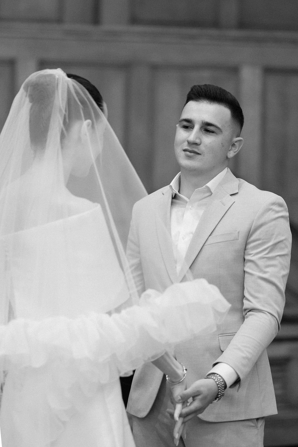 A couple in wedding attire share a romantic moment as the bride's veil flows in the breeze.