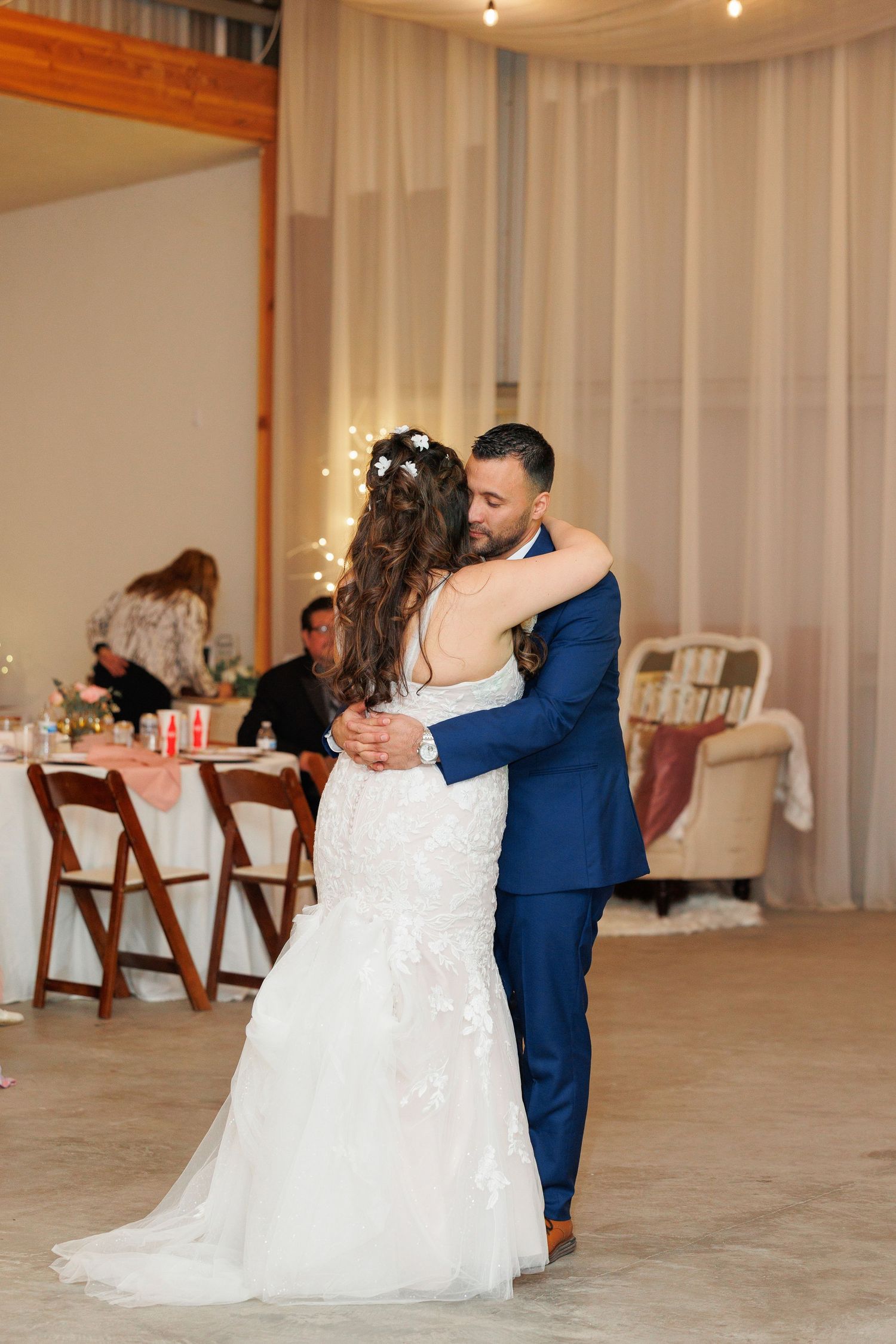 A romantic first dance between newlyweds in a beautifully decorated white reception hall.