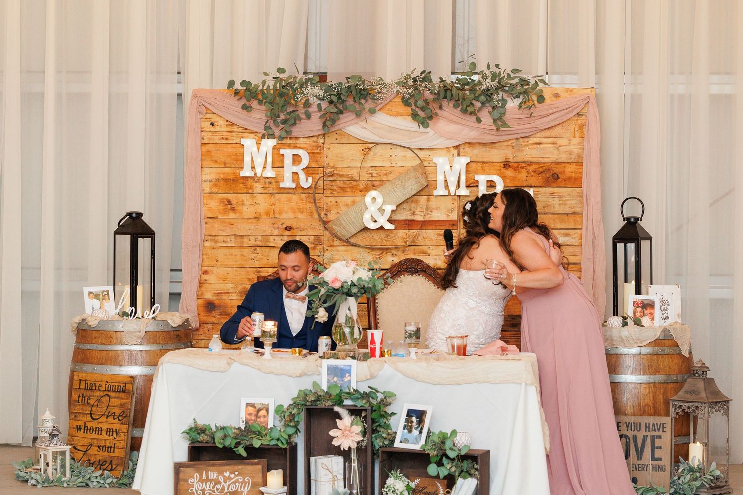 Wedding party poses in rustic venue with exposed brick walls, floral decor and Mr. and Mrs. signage.