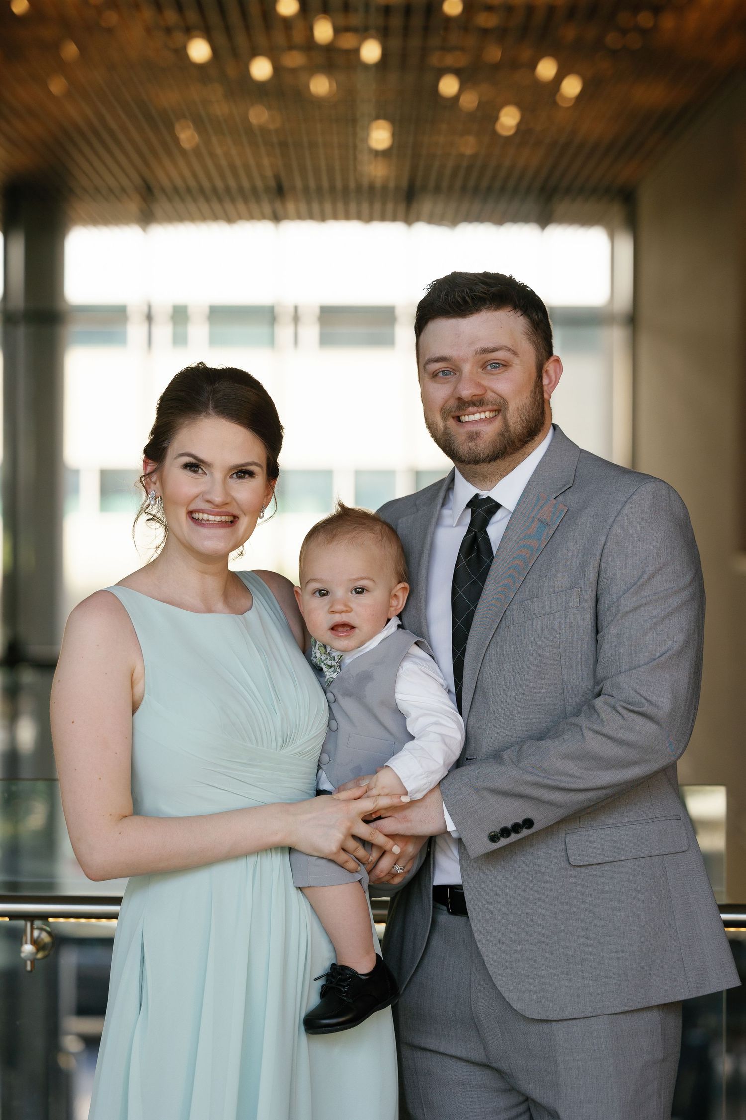 A family in formal attire shares tender moments in a series of indoor portraits with warm lighting and elegant decor.