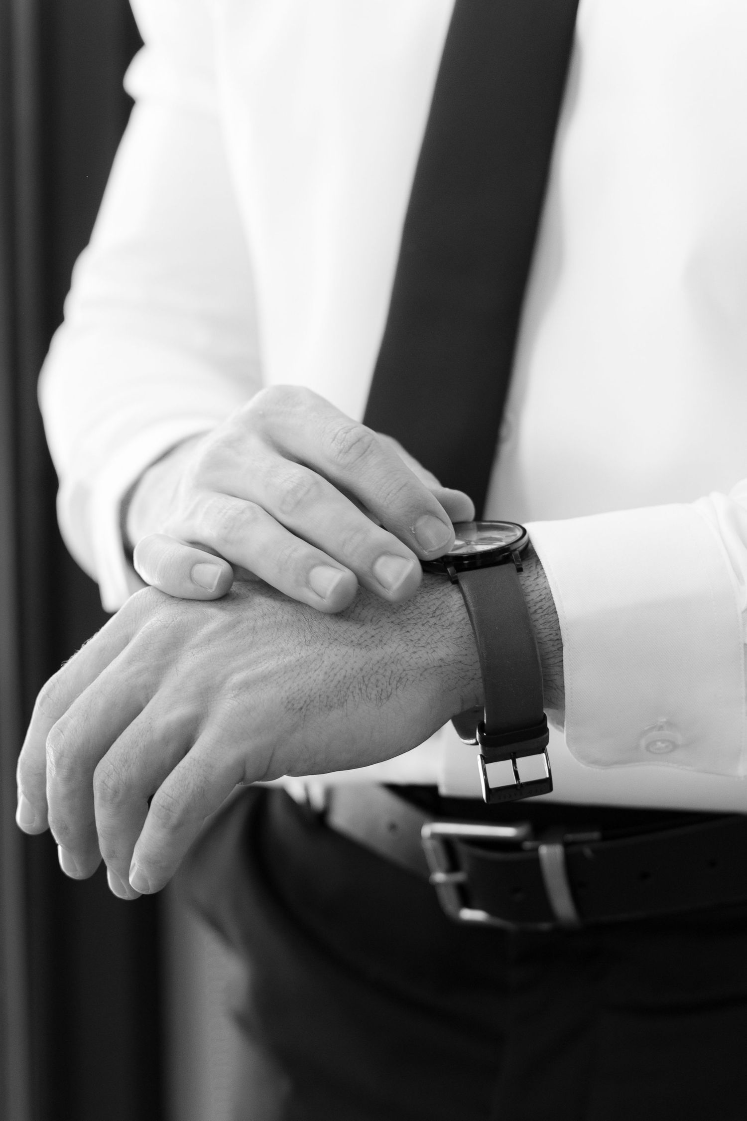 Black and white close-up photo showing hands adjusting watch straps in a sequence of four similar poses.
