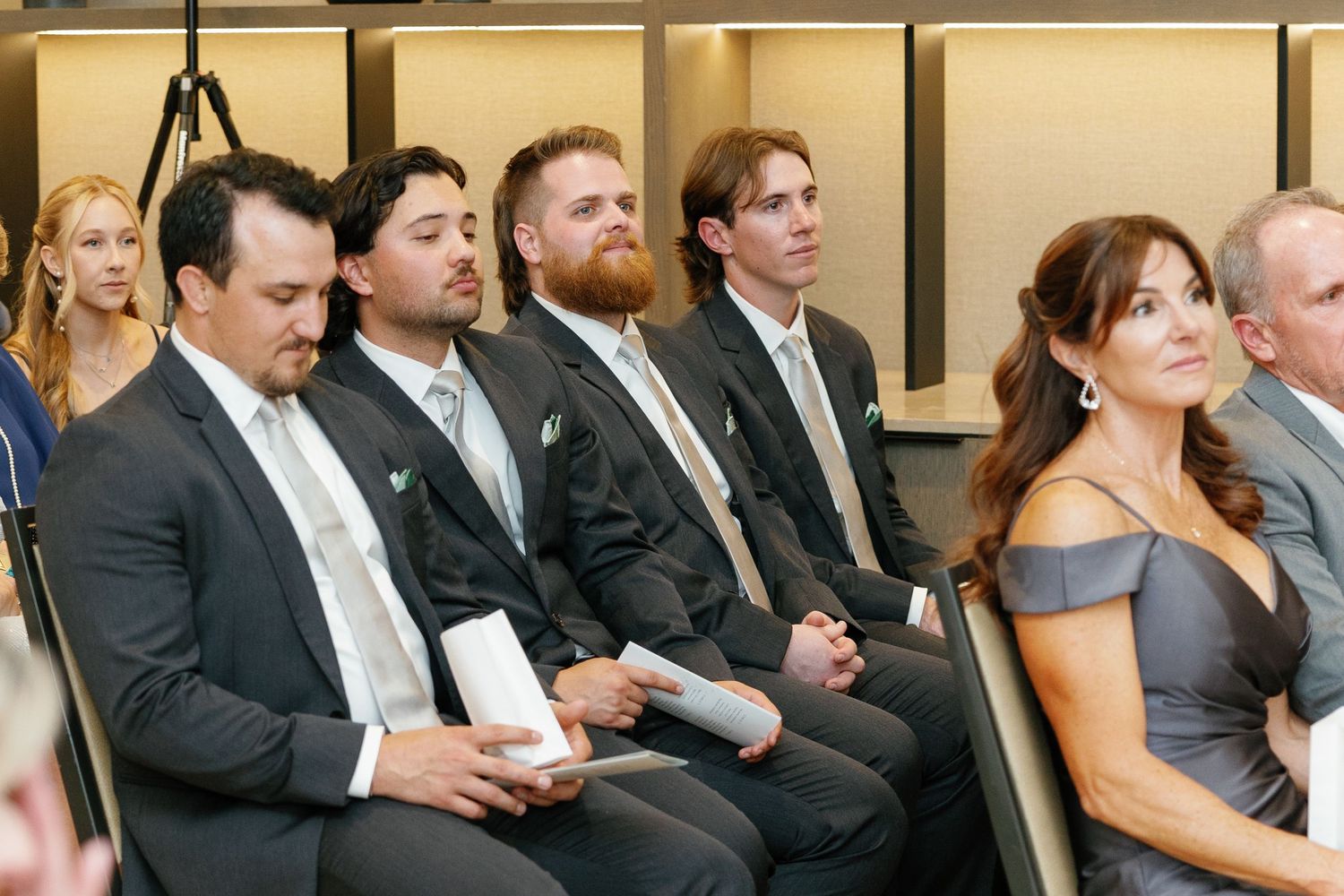 Wedding guests in formal attire seated in rows during a ceremony.