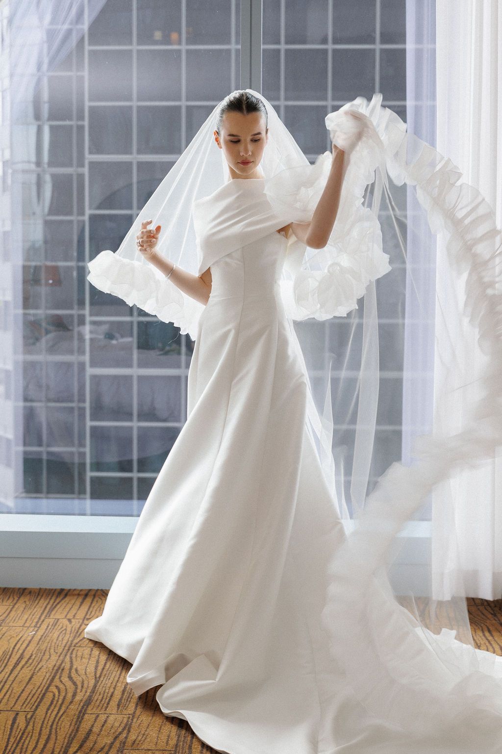 Dynamic dance movements captured in white flowing dress against bright window backdrop in modern studio space.