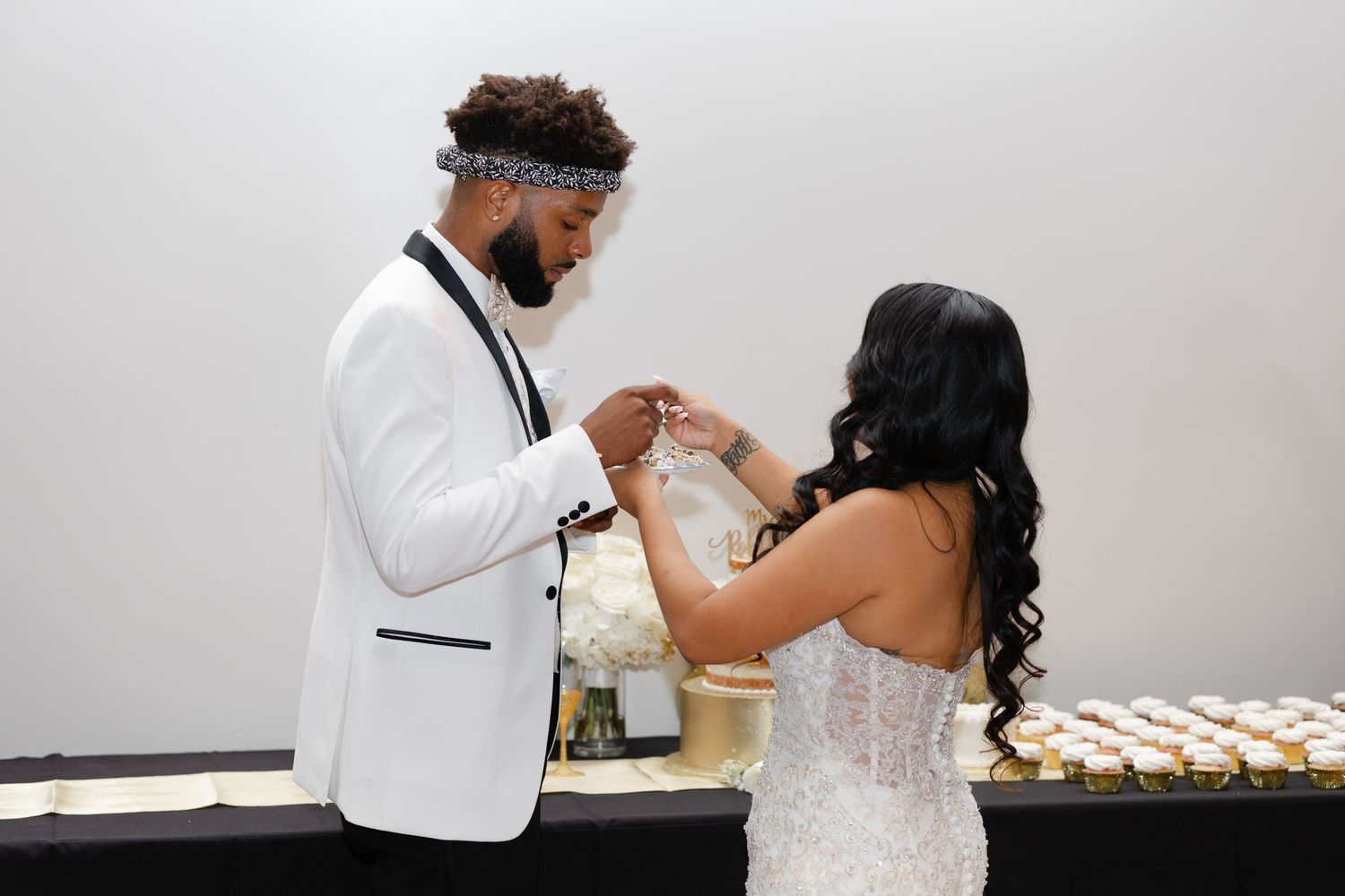 A couple shares an intimate moment during their wedding reception while feeding each other cake.