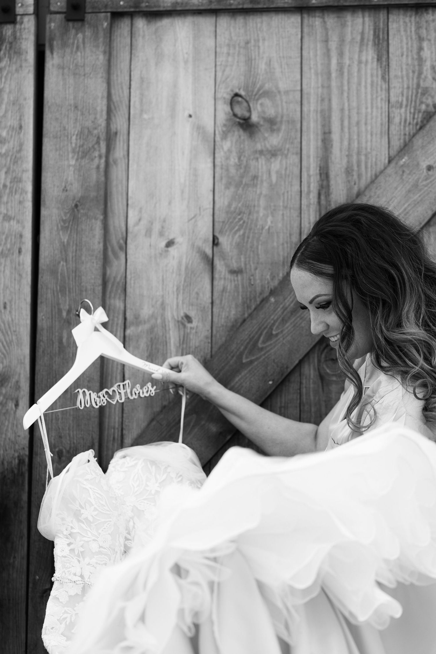 A series of artistic black and white photos showing the flowing movement of a white lace wedding dress against a wooden fence.