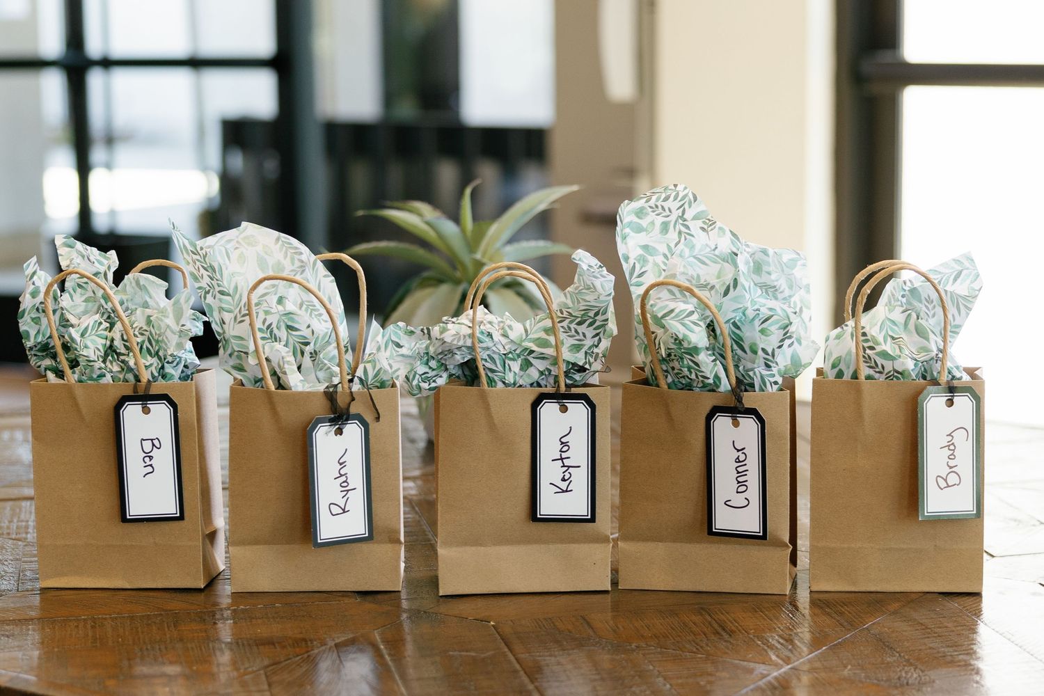 White paper place cards with floral designs arranged in a row on a wooden surface for wedding reception seating.
