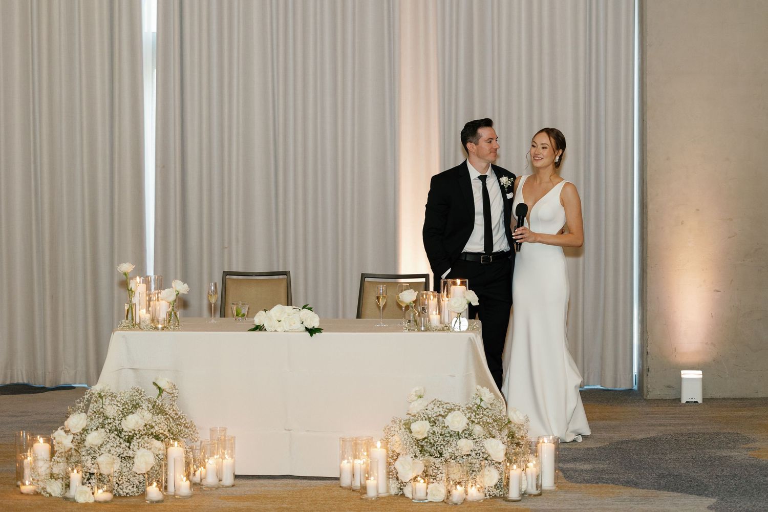 Elegant wedding ceremony setup with soft candlelight and white floral arrangements in a modern indoor venue.