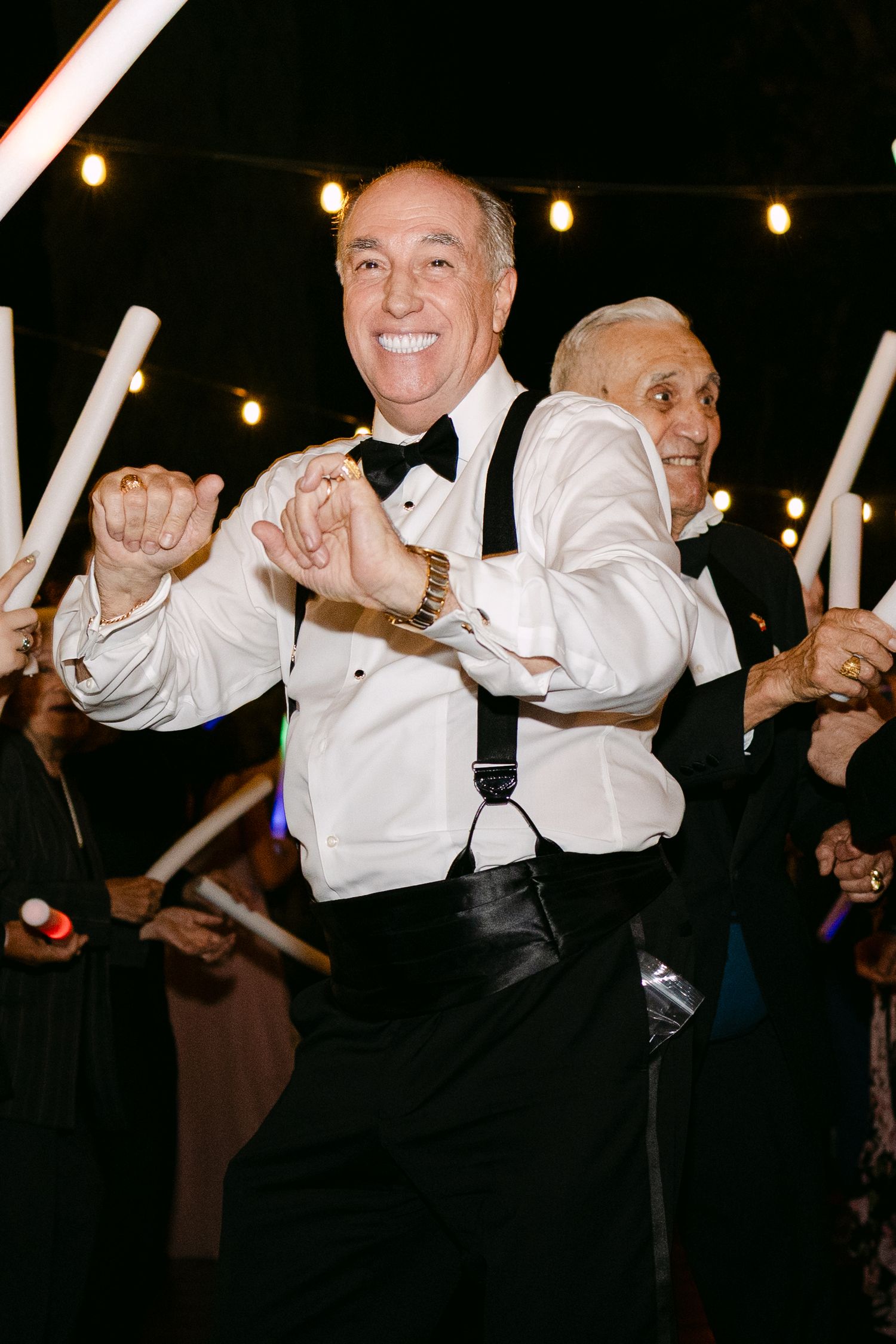 A group wearing white shirts and dark pants perform a synchronized dance routine at a celebration.
