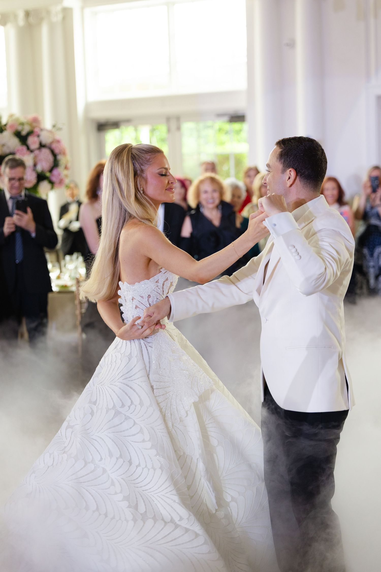 A couple performs a romantic dance at their wedding reception while guests watch in the background.