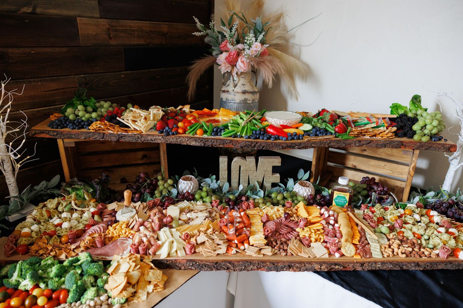 A rustic wooden table display showcases an abundant spread of fresh fruits, vegetables, and prepared dishes.
