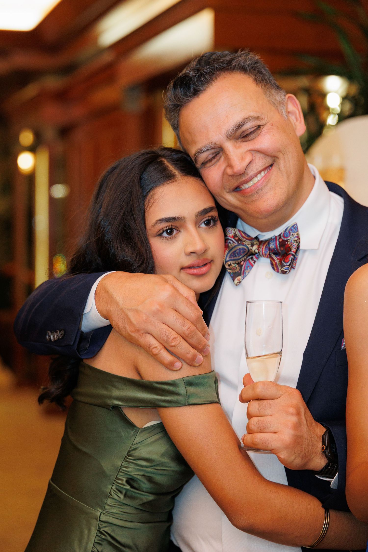 A couple shares an intimate dance moment at an indoor venue with warm lighting and formal attire.