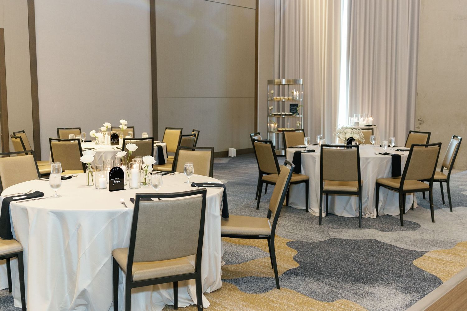Elegant banquet hall with cream-colored chairs and white tablecloths arranged in rows for a formal event.