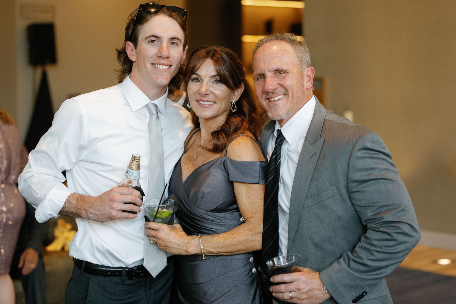 People in formal attire celebrating and posing together at a social gathering or event.