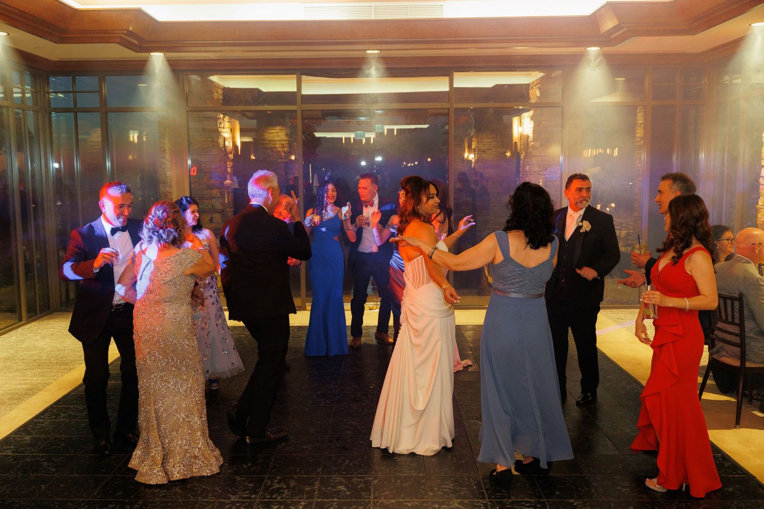 Couples dance together at an elegant ballroom reception with warm lighting and festive atmosphere.
