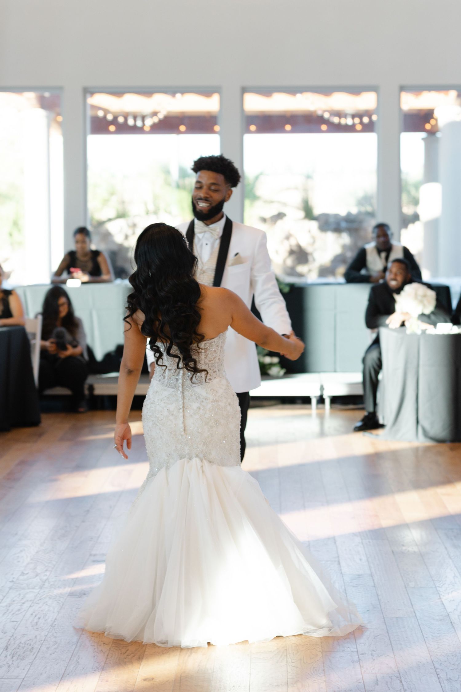 A couple shares their first dance as newlyweds on a polished wooden dance floor at their wedding reception.