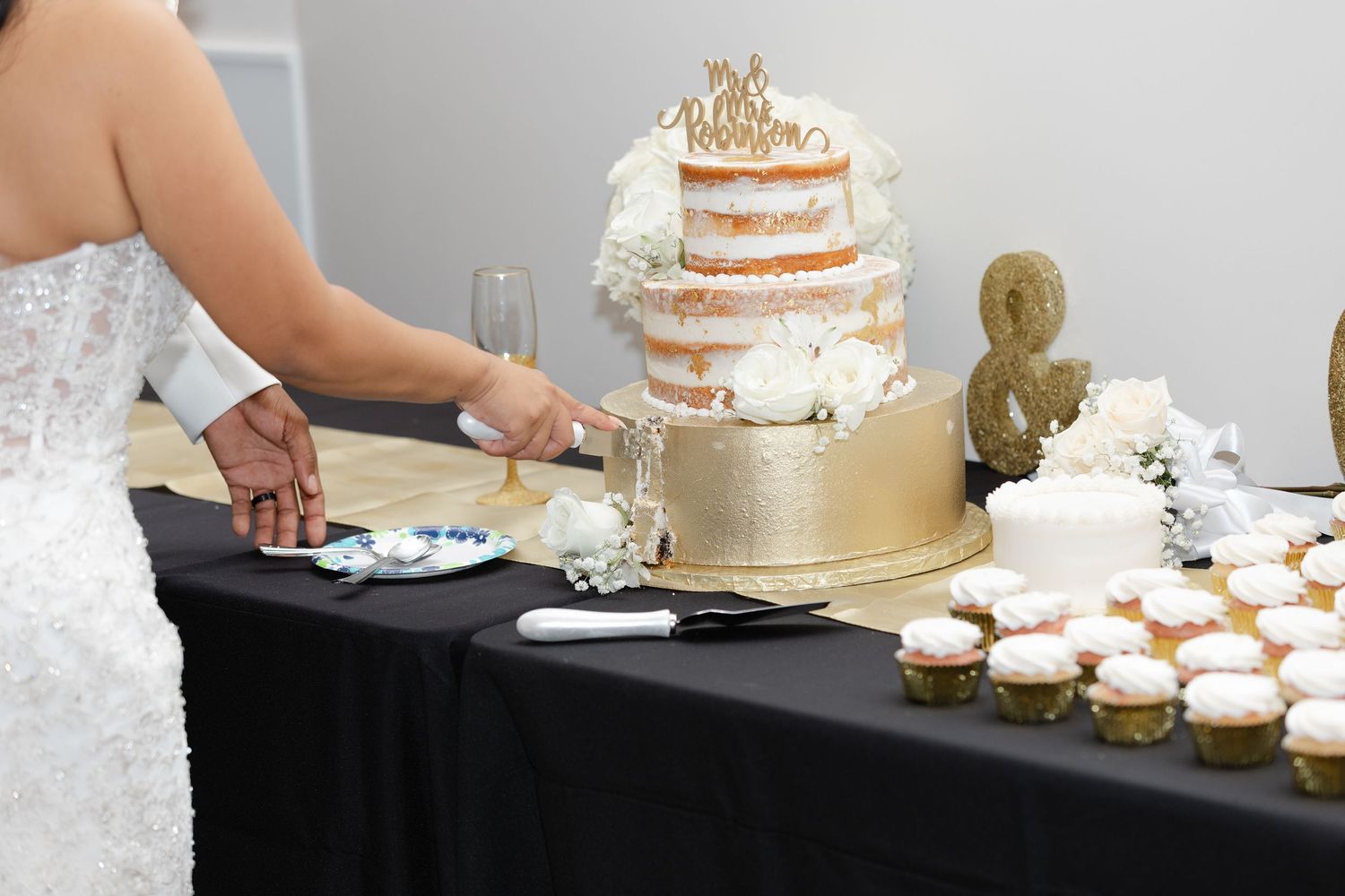 A row of elegant naked wedding cakes with minimal frosting displayed on white stands at a dessert table.