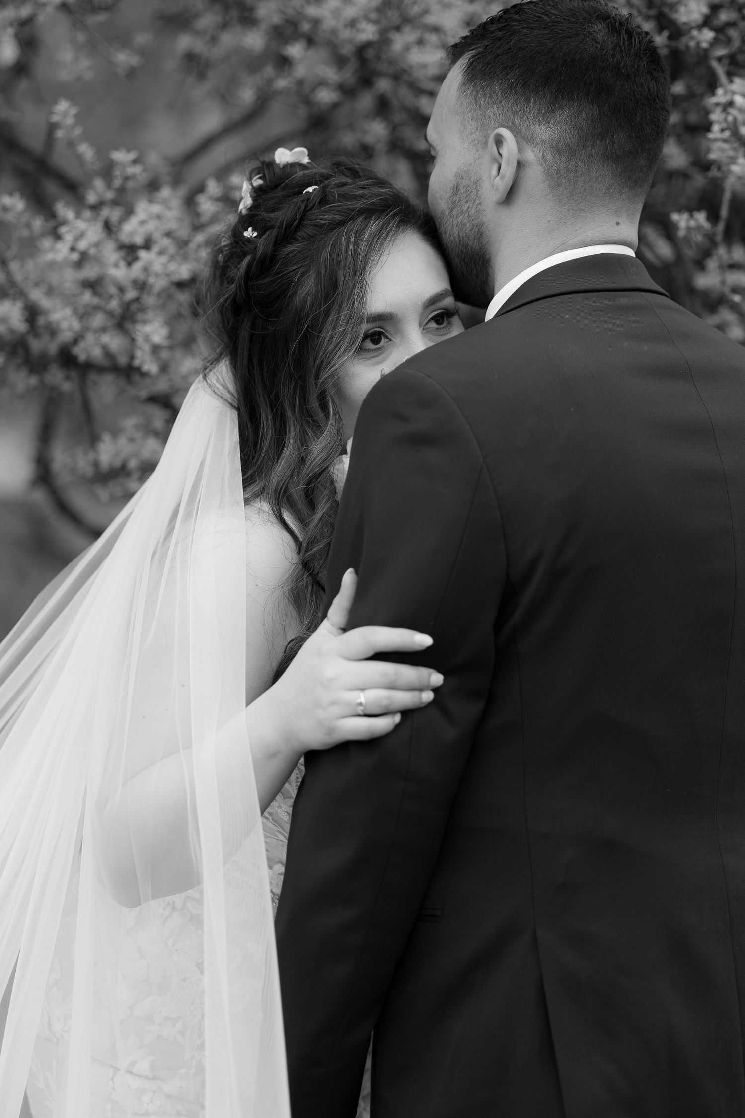 A romantic black and white wedding sequence showing a couple embracing in a garden setting with delicate blossoms.