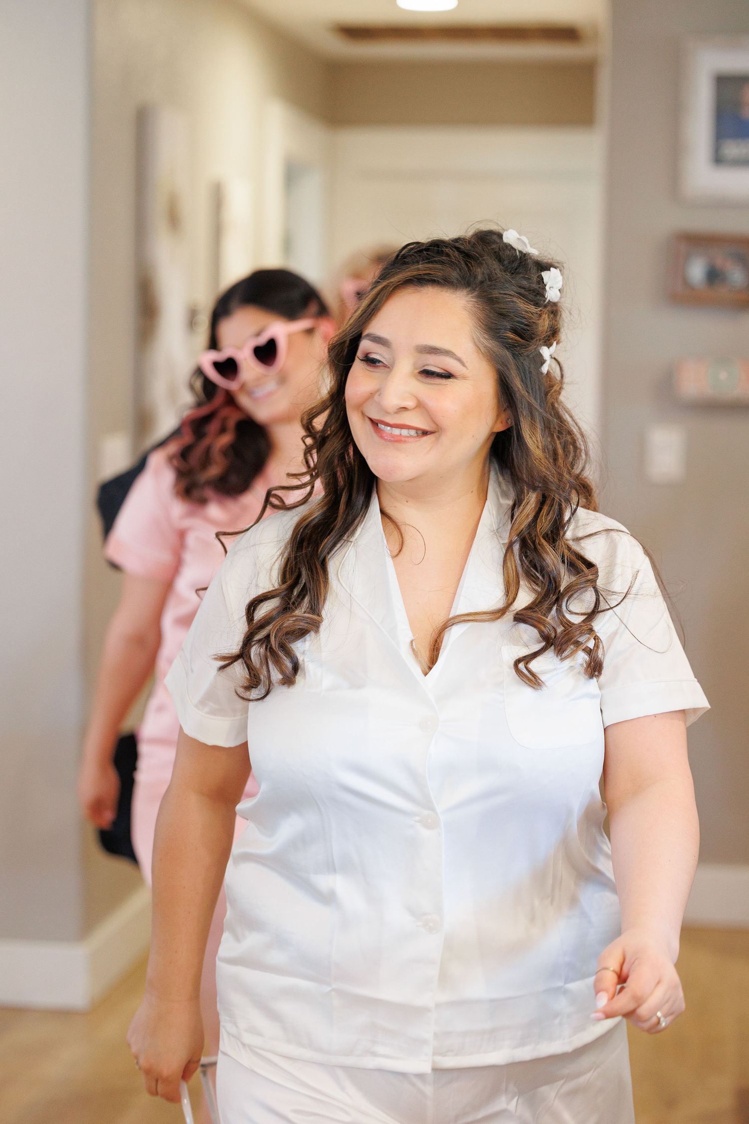 A person in a white button-down shirt laughs joyfully while dancing in a bright indoor space.