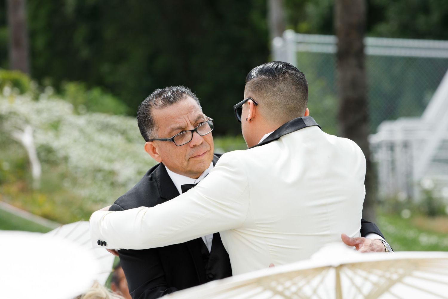 Two people in formal attire having a conversation while seated outdoors on a sunny day.