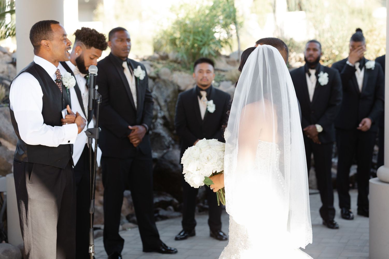 Wedding ceremony guests and bridal party gathered outdoors in formal attire for a celebration.