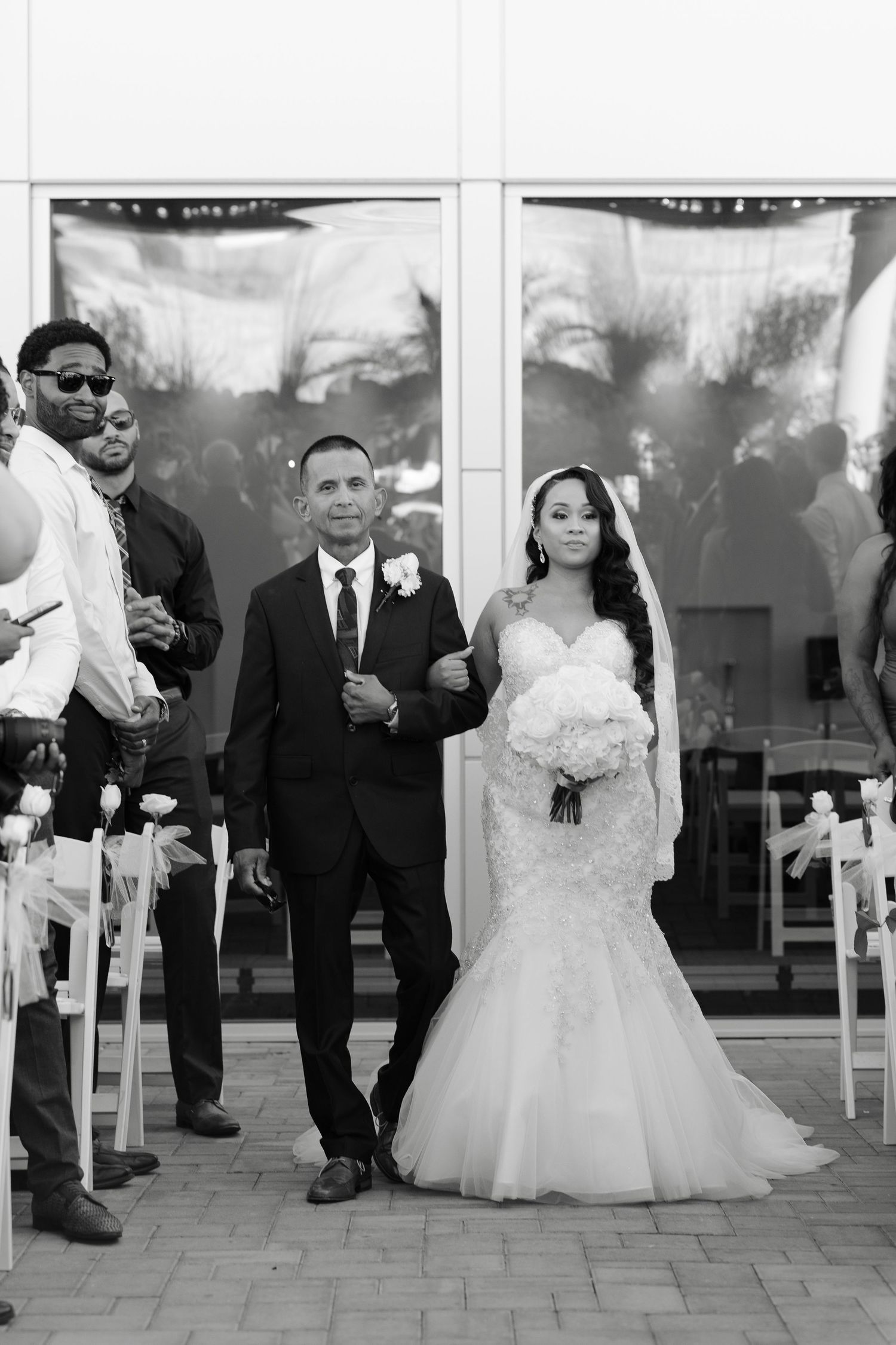 Black and white collage of wedding moments showing joyful dancing and celebration on a paved outdoor venue.