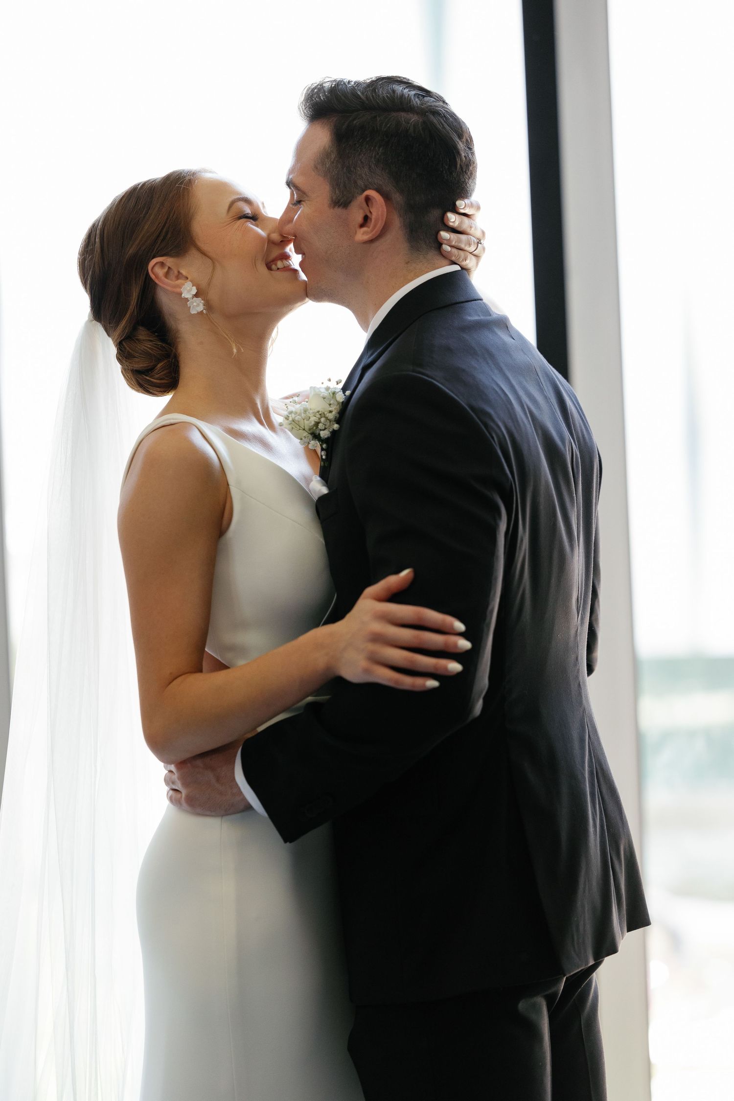 Three sequential photos show a romantic wedding kiss between newlyweds in front of bright windows.