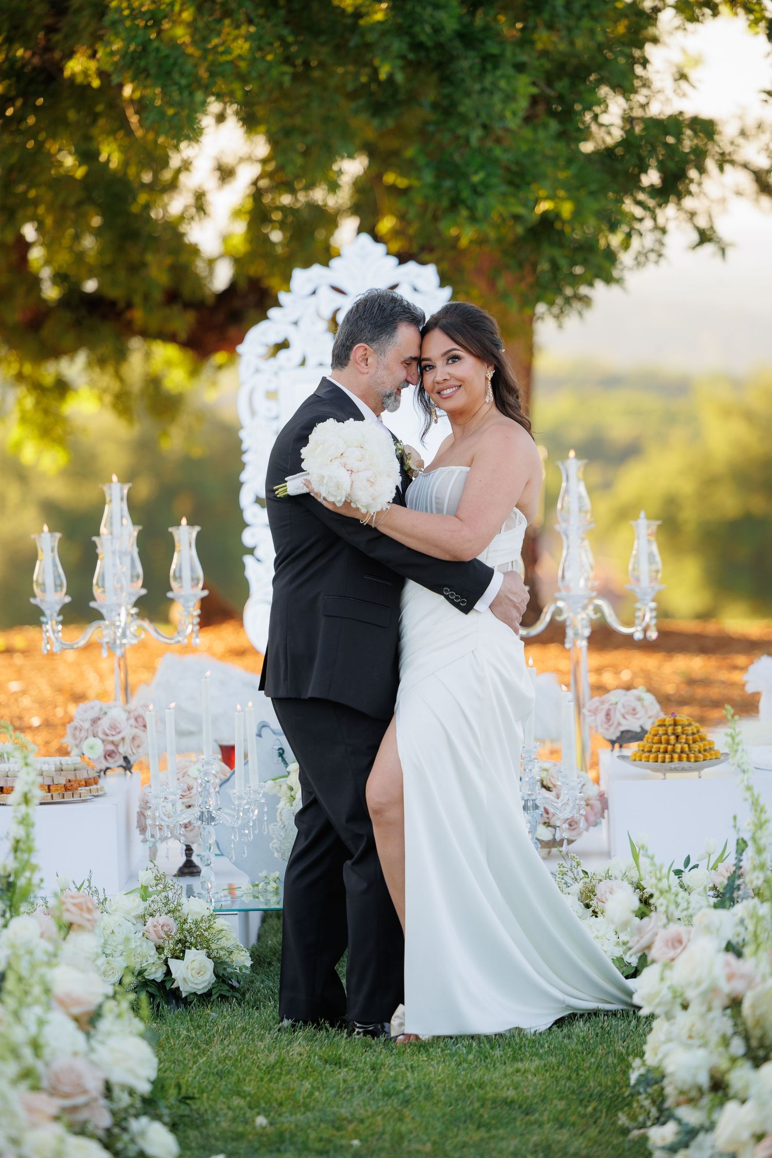 Elegant outdoor wedding reception setup with crystal candelabras and white floral arrangements at sunset.