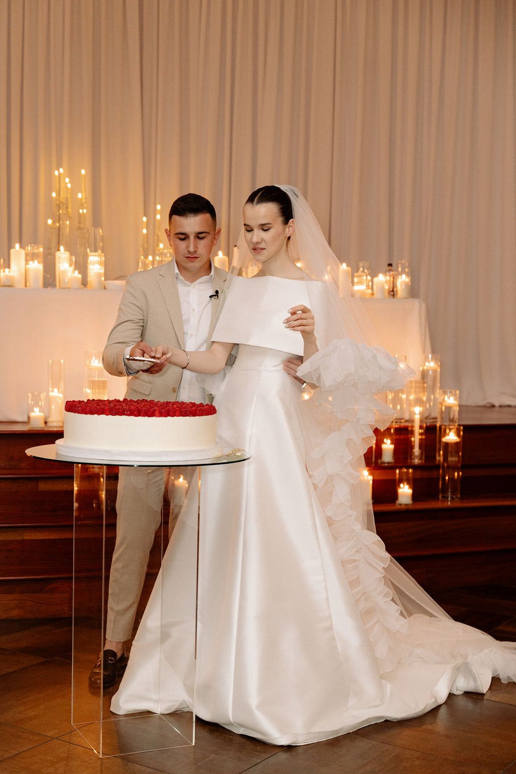 Wedding reception scene with glowing candles and white drapery creating a romantic atmosphere.