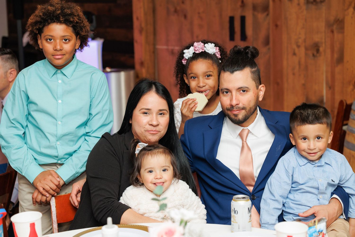 A group of people in formal attire gather together for a family photo session wearing coordinated blue and white outfits.